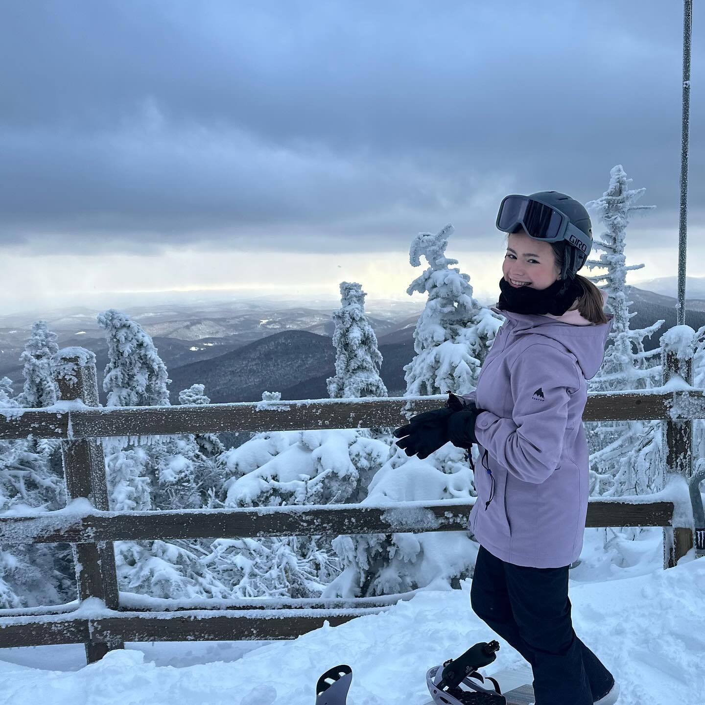 Lily on the summit of a snow-covered mountain, in her helmet and goggles